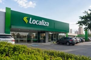 Fachada moderna de uma unidade da Localiza com o nome e logotipo em letras brancas sobre fundo verde, carros estacionados em frente e céu claro ao fundo.